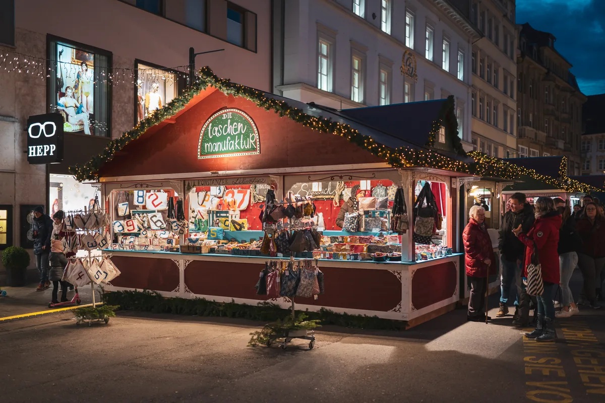 Festlich beleuchteter Kunsthandwerksstand auf dem Weihnachtsmarkt am See